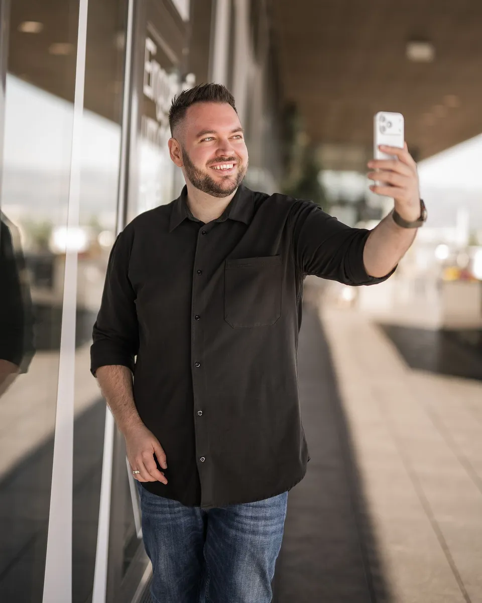 Philipp Unterholzer filmt sich lächelnd mit dem iPhone